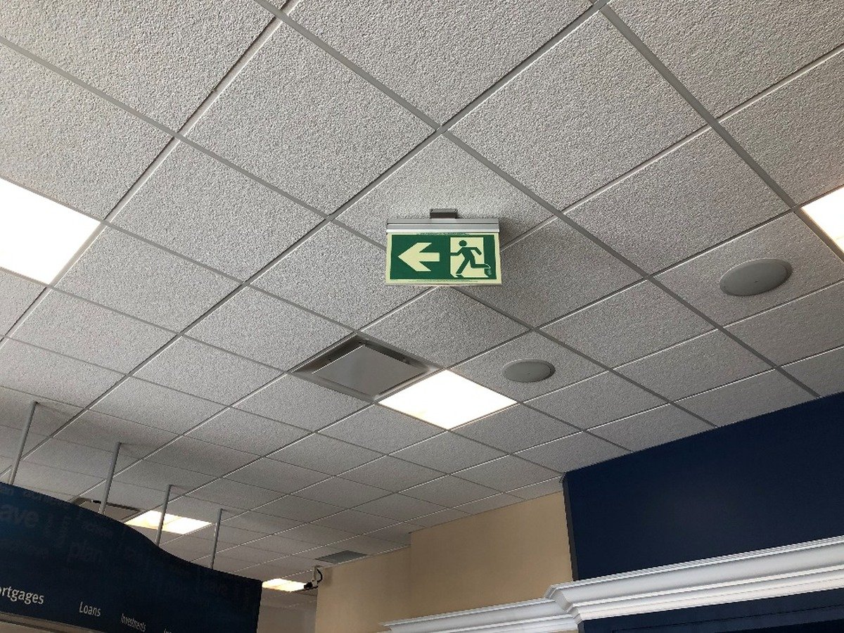 Photoluminescent Running Man exit sign installed in a commercial facility